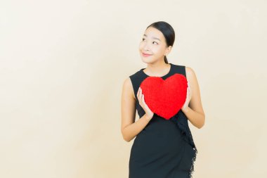 Portre güzel Asyalı genç kadın gülümsüyor kalp yastığı şeklinde renk arkaplan
