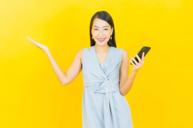 Renkli arka planda akıllı cep telefonuyla güzel Asyalı kadın gülümsemesi