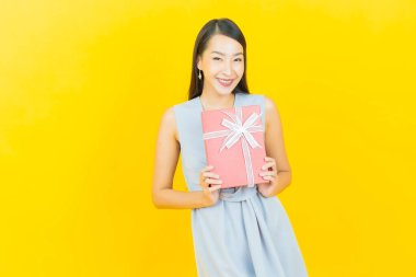 Güzel bir Asyalı kadının portresi. Arka planda kırmızı hediye kutusuyla gülümsüyor.
