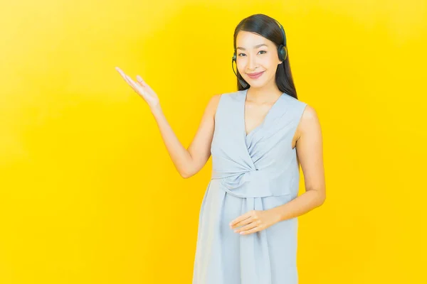 具有黄色背景的呼叫中心客户服务中心的形象漂亮的亚洲年轻女子 — 图库照片