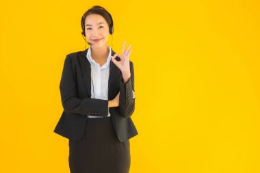 Portre güzel genç Asyalı kadın kulaklık ya da çağrı merkezi için kulaklık ya da tele pazarlama sarı izole arka planda.