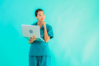 Mavi izole arka planda dizüstü bilgisayarı olan güzel Asyalı doktor kadın portresi.