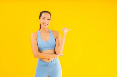 Sarı izole edilmiş arka planda spor giysili güzel Asyalı kadın portresi egzersize hazır.