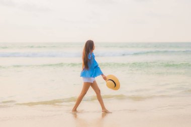 Güzel bir Asyalı kadın portresi. Gün batımında deniz kıyısında rahatça gülümse.