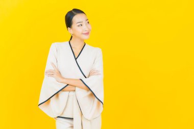 Portre güzel genç iş kadını gülümseyen ve eylem sarı arka planlı Asyalı kadın