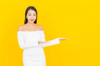 Portre güzel genç iş kadını gülümseyen ve eylem sarı arka planlı Asyalı kadın