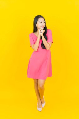 Asyalı güzel bir kadının portresi. Sarı arka planda hareketli gülümsüyor.