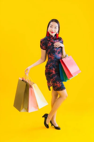 肖像画美しい若いアジアの女性は中国のドレスでショッピングバッグ スマートフォン クレジットカードで中国の旧正月に黄色の隔離された背景 — ストック写真