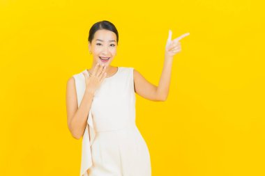 Asyalı güzel bir kadının portresi. Sarı arka planda hareketli gülümsüyor.