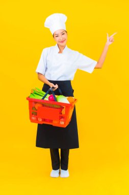 Sarı izole arka planda süpermarketten alınmış market sepeti olan güzel Asyalı bir şef kadın portresi.