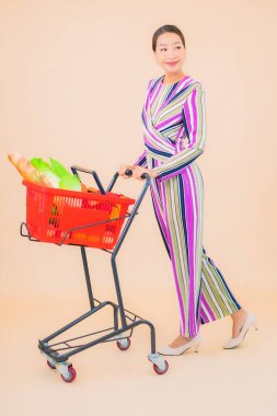 Marketten aldığı alışveriş sepetiyle güzel bir Asyalı kadının portresi. Renkli, izole arka plan.