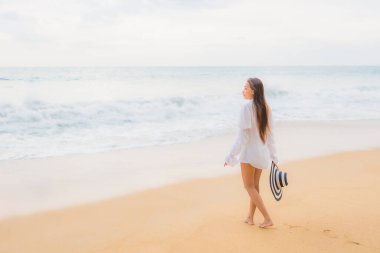 Güzel bir Asyalı kadın portresi deniz kenarında tatil yaparken rahatlar.