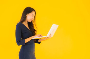 Bilgisayarı ya da bilgisayarı sarı izole edilmiş güzel Asyalı kadın portresi.