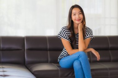 Güzel bir Asyalı kadın portresi. Mutlu bir gülümseme. Oturma odasındaki kanepede rahatla.