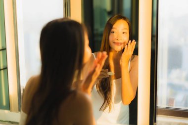 Güzel bir Asyalı kadın portresi. Banyo içinde yüzüne ve yüzüne krem sür.