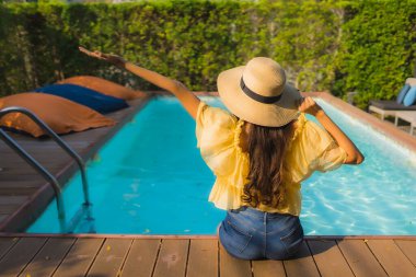 Asyalı genç bir kadının portresi mutlu bir gülümseme otel tatil beldesinde yüzme havuzunda rahatlamak