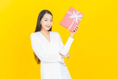 Güzel bir Asyalı kadının portresi. Arka planda kırmızı hediye kutusuyla gülümsüyor.