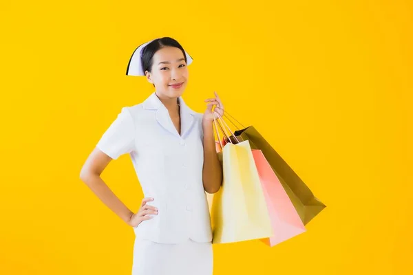 肖像画美しいです若いですアジアの女性タイ看護師とともにショッピングバッグとクレジットカード上の黄色隔離された背景 — ストック写真