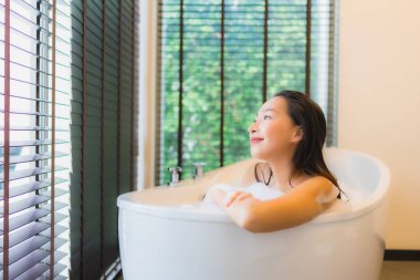 Güzel bir Asyalı kadın portresi mutlu bir gülümseme rahatla banyo küvetinde banyo yap.