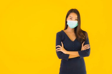 Koronavirüsten korunmak için maske takmış güzel Asyalı bir kadın portresi ve sarı izole edilmiş arka planda 19 numara.