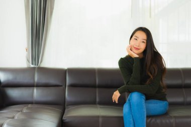 Güzel bir portre. Genç Asyalı kadın. Oturma odasındaki kanepede rahatla.