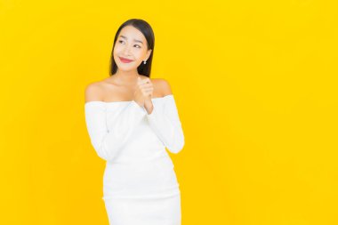 Portre güzel genç iş kadını gülümseyen ve eylem sarı arka planlı Asyalı kadın