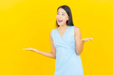 Asyalı güzel bir kadının portresi. Sarı arka planda hareketli gülümsüyor.