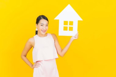 Sarı arka planda ev ya da kağıt tabelalı güzel Asyalı kadın portresi