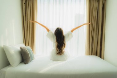 Genç Asyalı mutlu gülümseme. Yatak odasında iç tarafta rahatla.