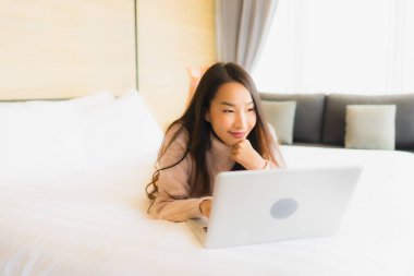 Yatak odasının iç kısmında dizüstü bilgisayar kullanan güzel Asyalı kadın portresi.