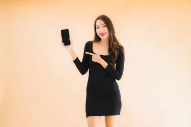 Güzel Asyalı genç bir kadının portresi mutlu bir şekilde gülümsüyor renkli arka planda akıllı cep telefonu kullan