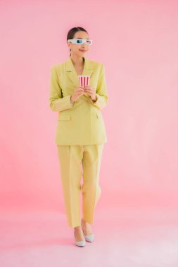 3D gözlüklü ve patlamış mısırlı güzel Asyalı kadın renkli arka planda film izlemeye hazır.