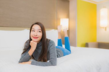 Güzel bir Asyalı kadın portresi. Rahatlayın, gülümseyin. Yatak odasında dinlenin.