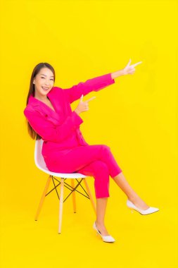 Güzel bir Asyalı kadın sarı arka planda gülümsüyor.