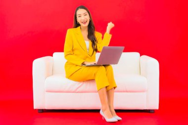 Güzel bir Asyalı kadın portresi kırmızı arka planda bilgisayar bilgisayarı kullanıyor.
