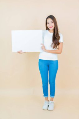 Güzel bir Asyalı kadın portresi. Krem arka planda boş beyaz ilan panosu kağıdı gösteriyor.
