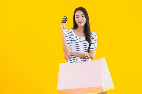 노란색외진 배경에 쇼핑백 카드를 가지고 아름다운 아시아 여자의 — 스톡 사진