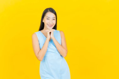 Asyalı güzel bir kadının portresi. Sarı arka planda hareketli gülümsüyor.