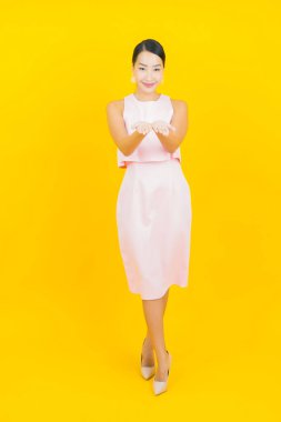 Asyalı güzel bir kadının portresi. Sarı arka planda hareketli gülümsüyor.