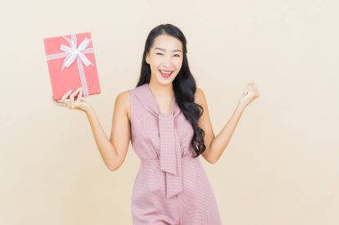 Güzel bir Asyalı kadının portresi. Arka planda kırmızı hediye kutusuyla gülümsüyor.