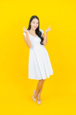 Asyalı güzel bir kadının portresi. Sarı arka planda hareketli gülümsüyor.