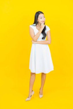 Asyalı güzel bir kadının portresi. Sarı arka planda hareketli gülümsüyor.