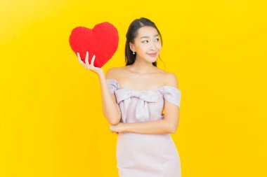 Portre güzel Asyalı genç kadın gülümsüyor kalp yastığı şeklinde renk arkaplan