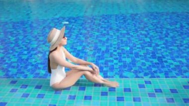 Güzel bir Asyalı kadın portresi tatil köyünde yüzme havuzunda rahatlıyor.