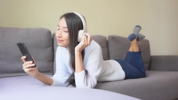 소파에서 헤드폰을 음악을 아름다운 아시아 여성의 — 비디오
