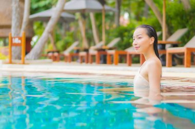 Güzel bir Asyalı kadın portresi tatil köyünde yüzme havuzunda rahatlıyor.