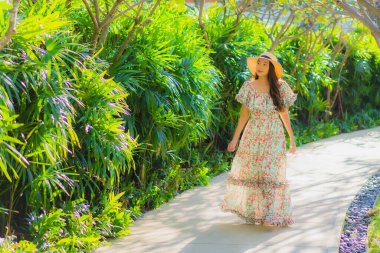 Güzel bir Asyalı kadın portresi. Mutlulukla yürüyor, bahçe manzarasının tadını çıkarıyor.