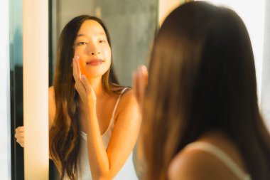 Güzel bir Asyalı kadın portresi. Banyo içinde yüzüne ve yüzüne krem sür.