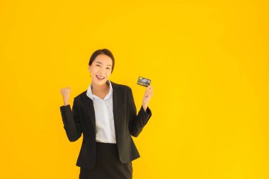 Sarı izole edilmiş arka planda kredi kartı olan güzel, genç Asyalı kadın portresi.