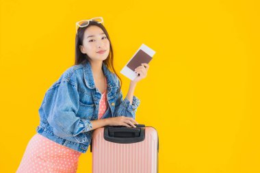 Çantalı güzel Asyalı kadın. Pasaportu ve sarı izole bir arka planda bilet.